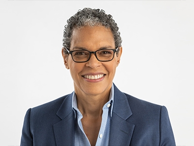 Michelle Adams, a smiling woman with close-cropped hair wearing a blue suit and glasses